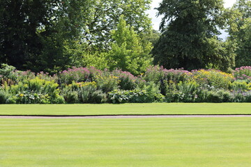Fototapeta premium View across a neatly mown lawn to a large flower bed