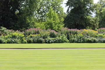 Fototapeten Khaki View across a neatly mown lawn to a large flower bed  © Francesca Leslie