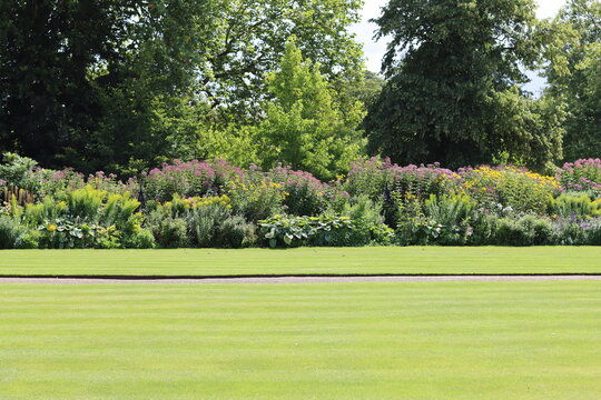 View across a neatly mown lawn to a large flower bed