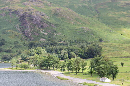 White cottage on a lake shore surrounded by hills