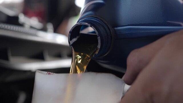 Mechanic changes the engine oil at a car repair shop.