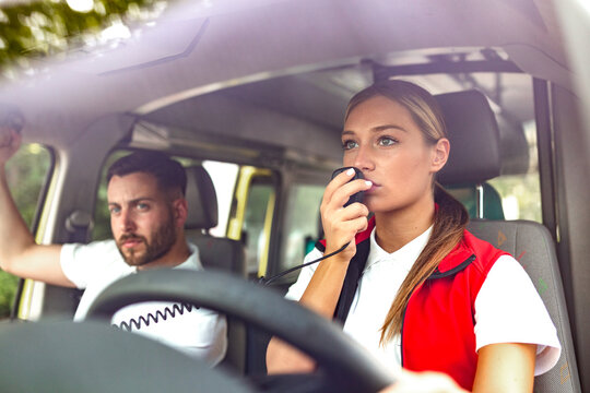 Emergency paramedic using radio transmitter while driving ambulance. Professional medical responder communicating with hospital during rescue mission. Healthcare and medicine concept, coordination