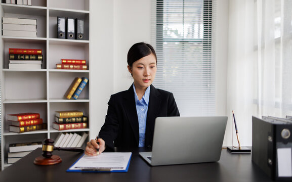 Female lawyer working at desk with laptop and legal documents