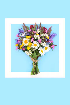 Beautiful Springtime flower bouquet background frame on blue with spring flowers. Tied natural posy for Mothers Day, Beltane festival, birthday card. Floral arrangement.