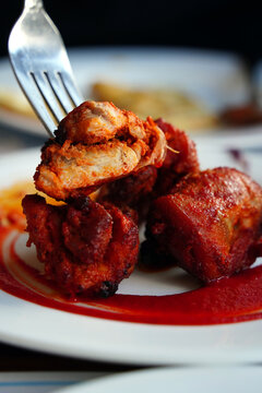 Authentic Indian Chicken Tikka served with spicy red sauce on a white plate.
