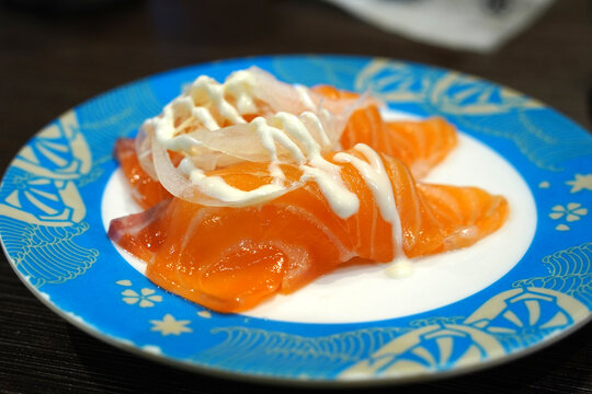 Fresh Salmon sushi (Sake Nigiri) topped with sliced onions and creamy mayonnaise sauce.