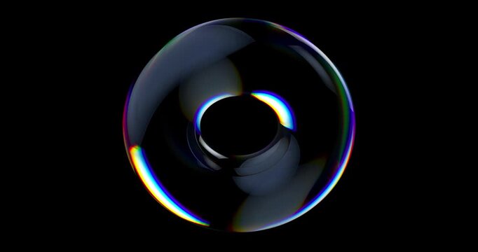 Smooth glass torus shape bending light into colorful spectral reflections against a dark background.