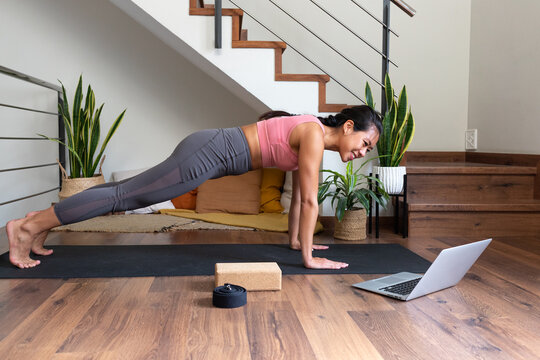 Woman doing plank exercise watching online yoga class at home
