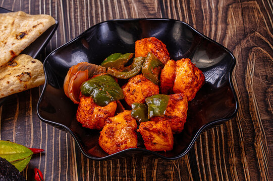 Indian Paneer Tikka Masala inl with Roti bread on a dark wooden table