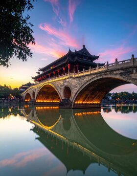 A stunning view of the Anshun Bridge in Chengdu, China, illuminated at dusk with a vibrant sunset reflection.
