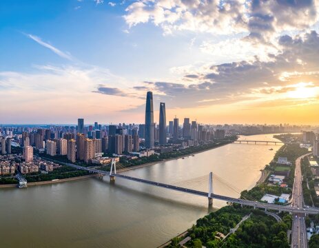 An aerial view showcases a sprawling cityscape with modern skyscrapers and a river winding through, bathed in the warm glow of a sunset.