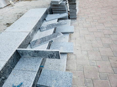 Construction process of installing grey granite stone tiles on outdoor stairs at a building site