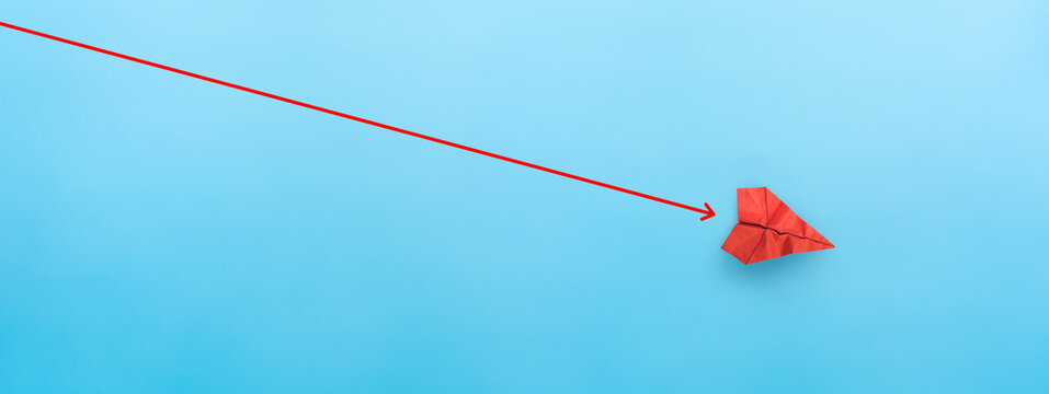 Red paper plane falling down with red arrow on blue background, representing business failure or economic crisis.