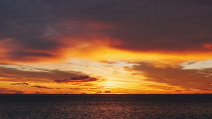 Obraz premium Sunset over sea with vibrant red and orange sky