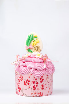 Close-up of pink floral cupcake with Easter egg and XB initials on white