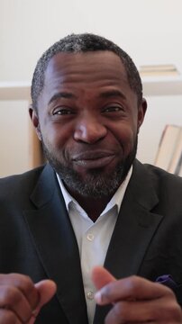 An African American man in a suit and tie gestures with his hands while speaking, conveying enthusiasm and engagement