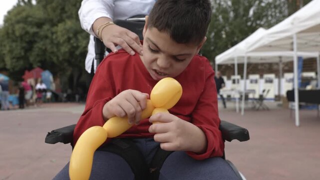 Boy with cerebral palsy playing with a yellow balloon animal