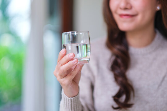 Closeup image of a woman holding a glass of drinking water at home