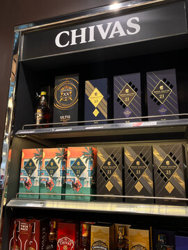 Various Chivas Regal whiskey bottles neatly arranged on a shelf. The colorful packaging includes different ages and varieties. Ideal for whiskey enthusiasts and collectors.