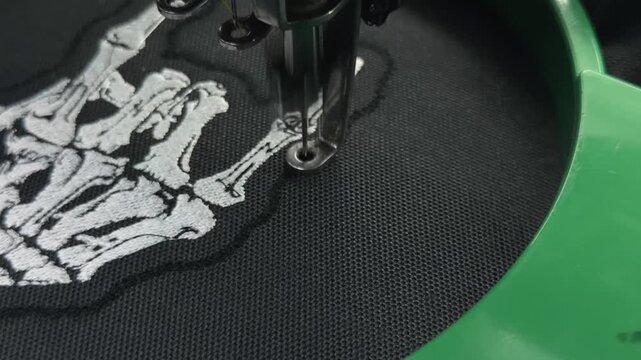 Extreme Macro Close Up: Automated Industrial Embroidery Needle Stitching Final Border on Skeleton Hand Patch Design Black Fabric Texture Handheld Slow Motion Authentic Production