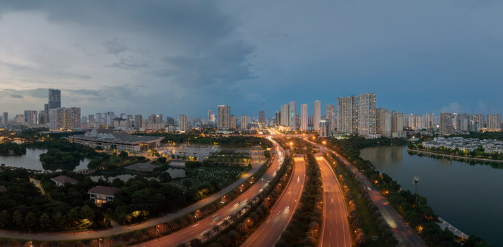 Panoramic drone view of Thang Long Boulevard stretching across Hanoi with expansive skyline, glowing traffic lines, and dramatic twilight clouds over the city