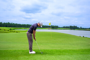 Professional young male golfer swings his club on scenic golf course.