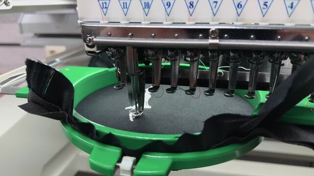 High-Tech Machine for Custom Logo Embroidery on Black Textile Material Professional Branding Service Apparel Personalization Process Handheld Slow Motion Authentic Marketing B-Roll Industry Scene