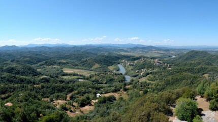 Obraz premium Green mountains rise against a blue sky with clouds, while a small village sits at the foot of the mountains in the valley below