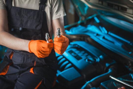 Auto mechanic installing a new spark plugs into the engine.