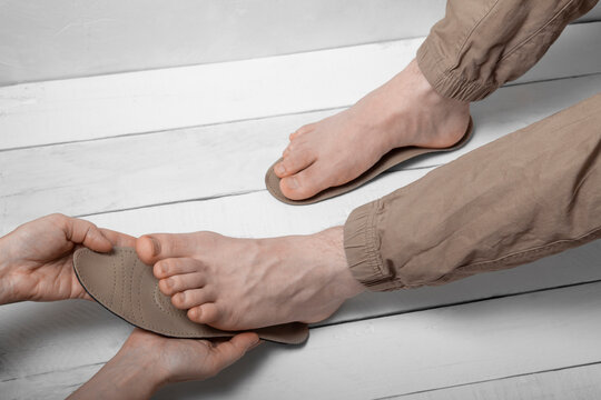 Top view of hand fitting orthopedic insole to foot for therapy