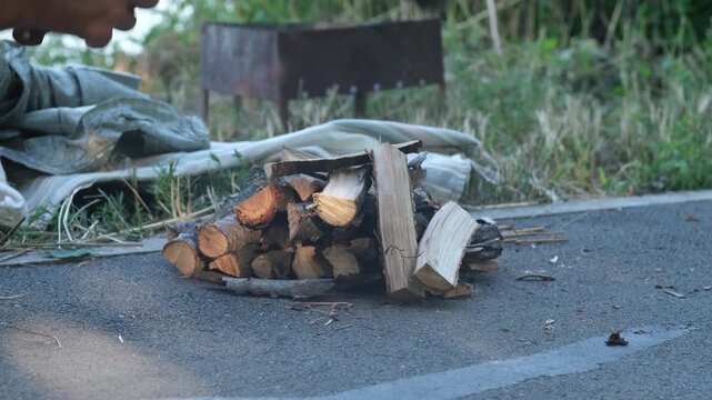 Close up of hands using large machete knife to chop firewood on ground outdoors. Concept of camping, survival, cooking outdoors
