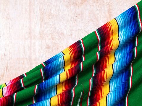 Colorful serape on wooden table. Typical colorful fabric from Mexico. Cinco de Mayo background.