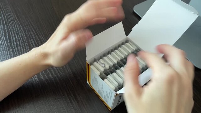 Careful placement of blister packs in boxes. Precise arrangement of pharmaceutical packs for secure storage. Systematic sealing and organizing of blister packs inside storage containers