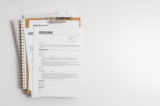 Resume documents placed on a clipboard and stack of paper documents representing job search, candidate evaluation, and recruitment process