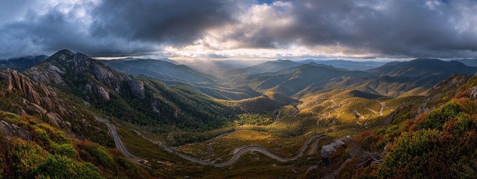 Panoramic view of dramatic overcast sky breaking to reveal sunlit valleys and