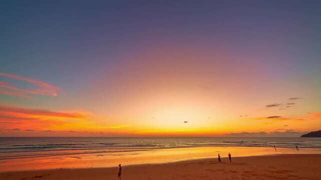 A breathtaking sunset over a tropical beach, casting golden hues across the sky and reflecting on the calm ocean waters. Silhouettes of people walking along the shore add a peaceful and serene 