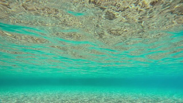 Glare of the sun on sandy bottom of sea, Movement forvard over sand seabed with ripples on water surface, on a sunny day, Waves above sand seabed with reflection on water surface