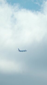 Passenger airplane flying through cloudy sky with soft light and distant perspective, commercial aviation and travel cost concept, vertical orientation. Air transport reflecting rising fuel prices and