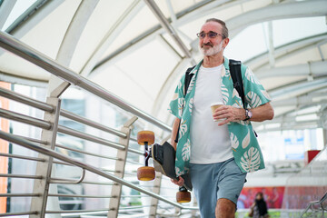 Happy senior man walking with electric skateboard in city © DG PhotoStock