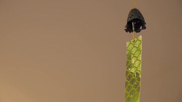 Close-up of Traditional Japanese Iron Wind Chime (Furin) with Green Paper Slip Swaying, Copy Space, Horizontal