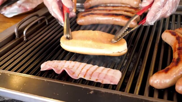 Close-up footage of raw, streaky bacon strips being cooked on a hot, cast-iron grill. The meat sizzles as the fat renders and smoke rises, creating appetizing grill marks.