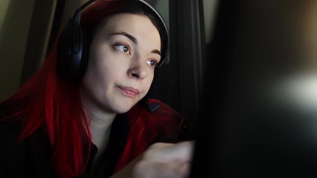 Female customer support agent is engaged in remote assistance during client interaction via video. Woman is speaking into camera. Lady printing on laptop keyboard with focused face deliver guidance 
