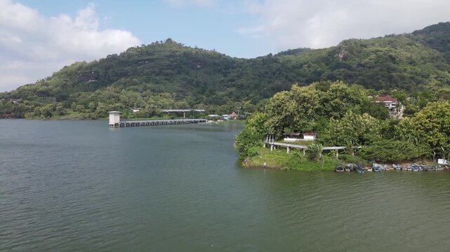 A cinematic dolly out drone shot captures the scale of the Gajah Mungkur Reservoir, revealing its infrastructure and the verdant mountain landscape