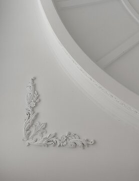 Luxury neoclassical interior details with white crown molding, ornate ceiling and vintage chandelier.
Elegant interior design featuring classical architectural elements.