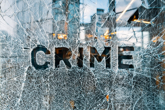 Glass screen full of shattered crazed glass with the word "CRIME" knocked out leaving a negative space