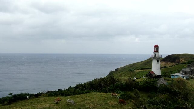 Aerial forward flight toward the historic Basco Lighthouse on a moody overcast day at Naidi Hills in Batanes, Philippines