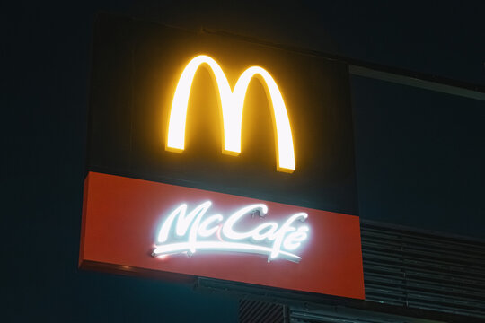 11 January 2026, Dubai, UAE: McDonald's and McCafe neon signs glowing on a fast food restaurant exterior at night, symbolizing global branding and business
