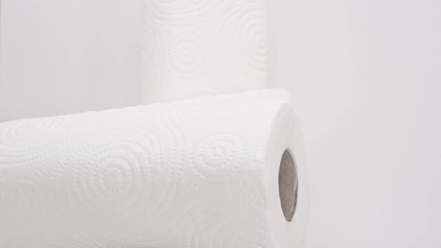 Paper rolls are stacked and arranged on a simple surface in a bright light setting to show different angles and details of the rolls