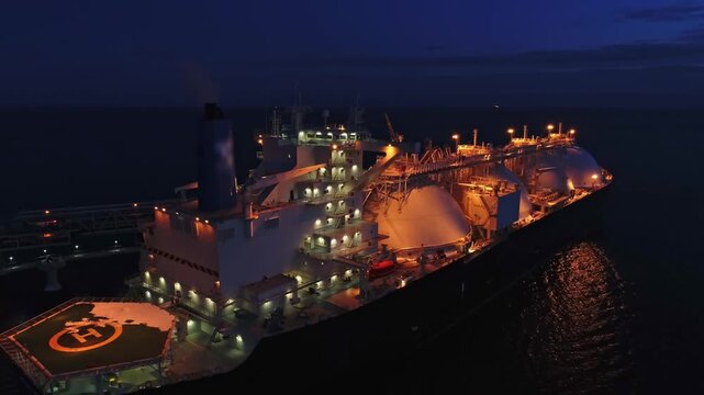 Aerial of Liquified Natural Gas LNG carrier moored to a small gas terminal at night. Fuel crisis. Sanctions