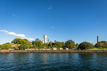 Obraz premium Cockatoo Island Camping Foreshore with Historic Water Tower and Chimney on Sydney Harbour